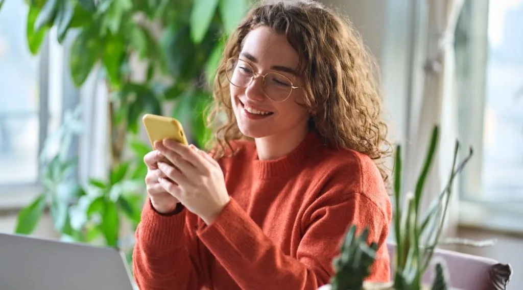 A woman happily accessing a website on her phone