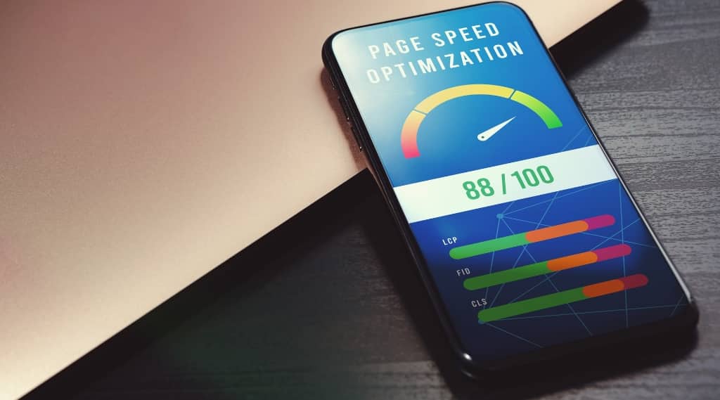 Smartphone showing 88/100 score for 7-second site speed test optimisation on a desk beside a laptop.