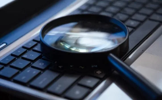 Magnifying glass placed on a laptop keyboard for search or analysis concept