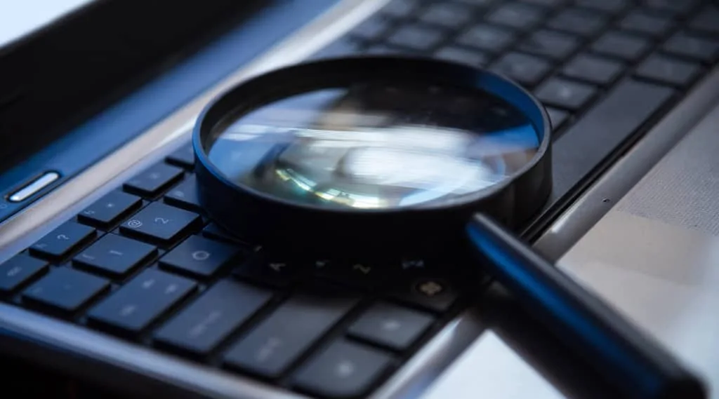 Magnifying glass placed on a laptop keyboard for search or analysis concept